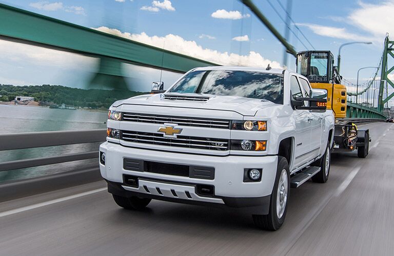 2019 Chevy Silverado 2500HD white front view towing construction equipment
