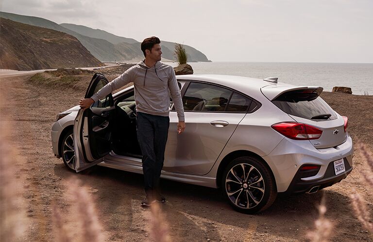 2019 Chevy Cruze silver hatchback side view with a young man stepping out