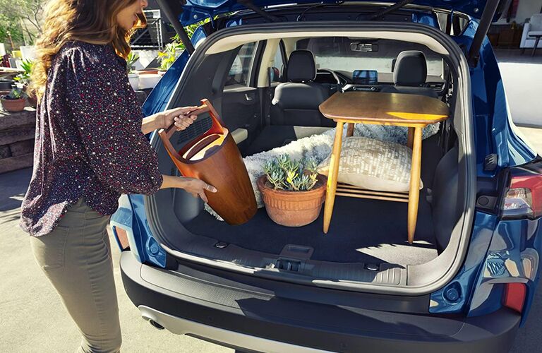 A woman loading items into the cargo area of a blue 2020 Ford Escape