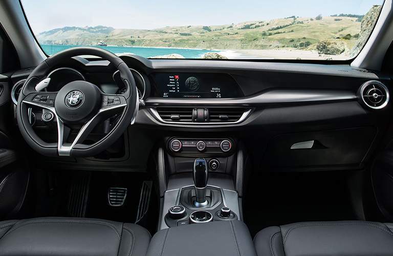 Steering wheel and dashboard of 2018 Alfa Romeo Stelvio with field in background