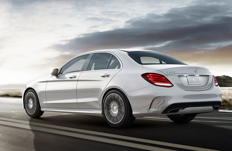 White 2018 Mercedes-Benz C300 driving on wet road during overcast afternoon