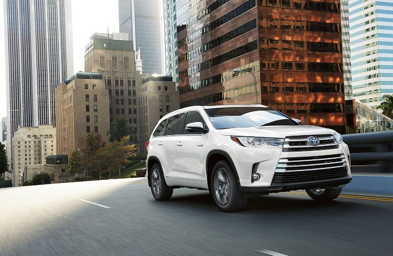 White 2017 Toyota Highlander Driving Down Urban Street