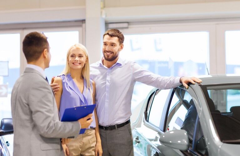 A photo of people working with a dealership's sales staff to buy a car.