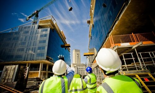 Men working on a construction site view of them from the back looking up at buildings