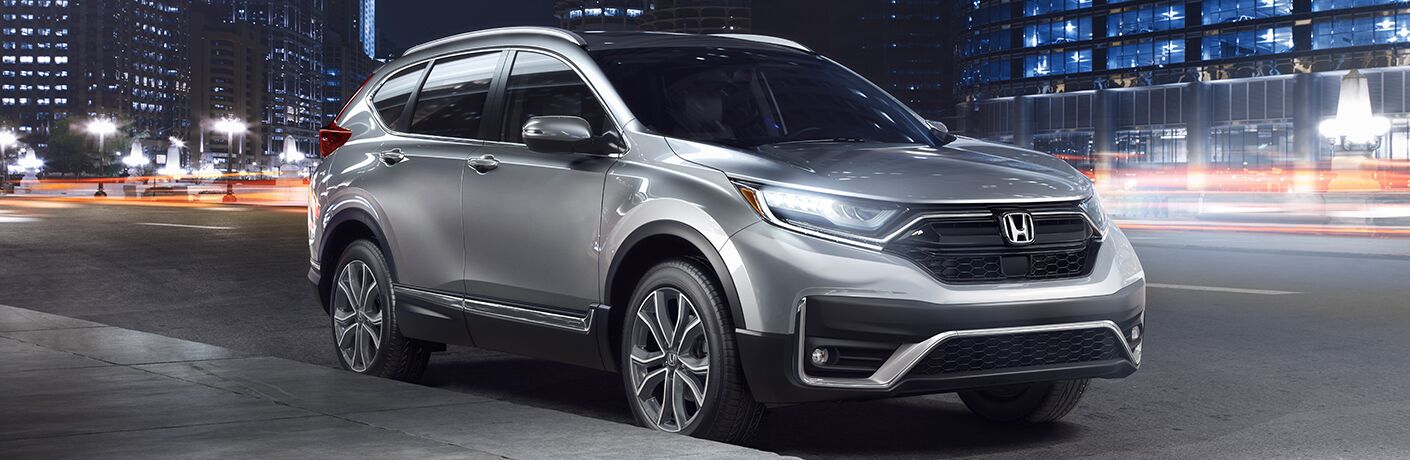 Silver 2020 Honda CR-V in a city at night by a sidewalk.