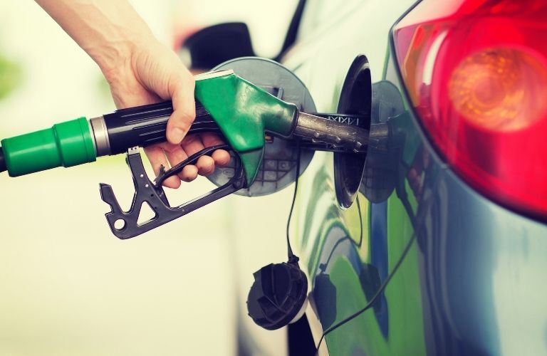 Oil being pumped into a fuel tank of a car