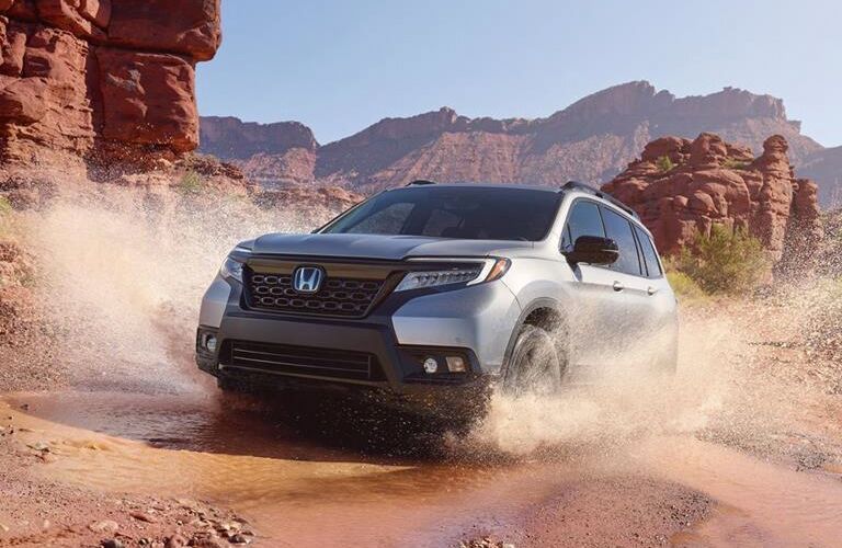 Silver 2019 Honda Passport Splashing Through a Puddle