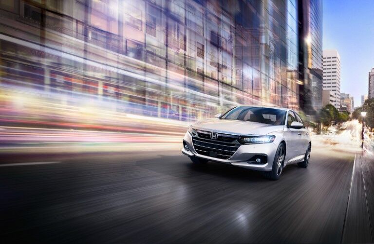 2021 Honda Accord Touring exterior shot with Platinum White Pearl paint color driving through a city at night as lights blur in the background