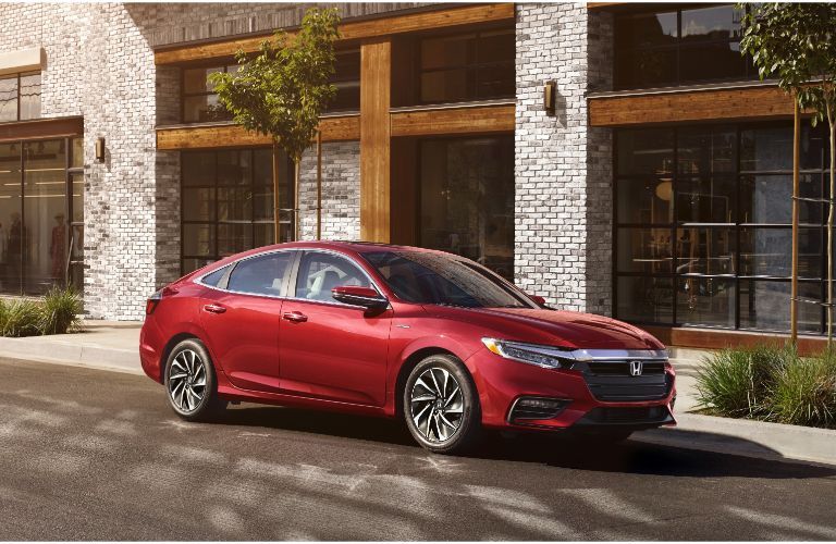 2021 Honda Insight exterior shot with Radiant Red Metallic paint color parked outside a fancy white and gray brick building