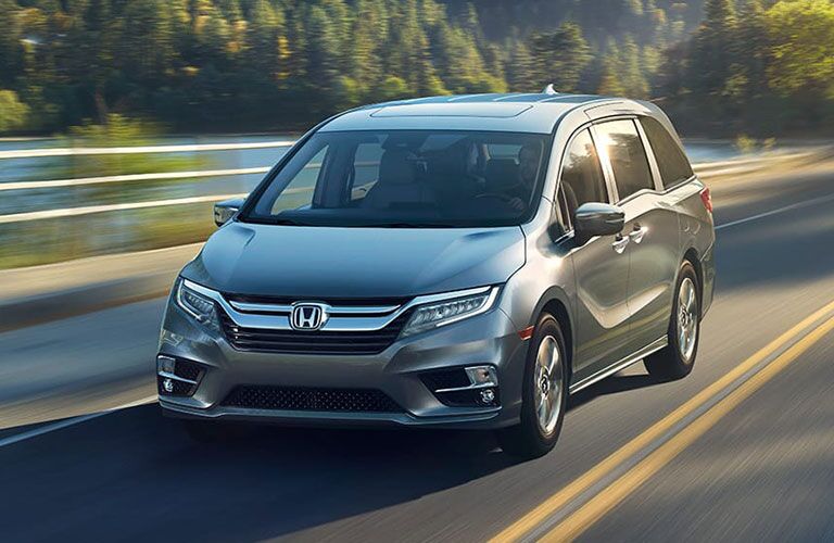 2018 Honda Odyssey driving across a bridge by trees