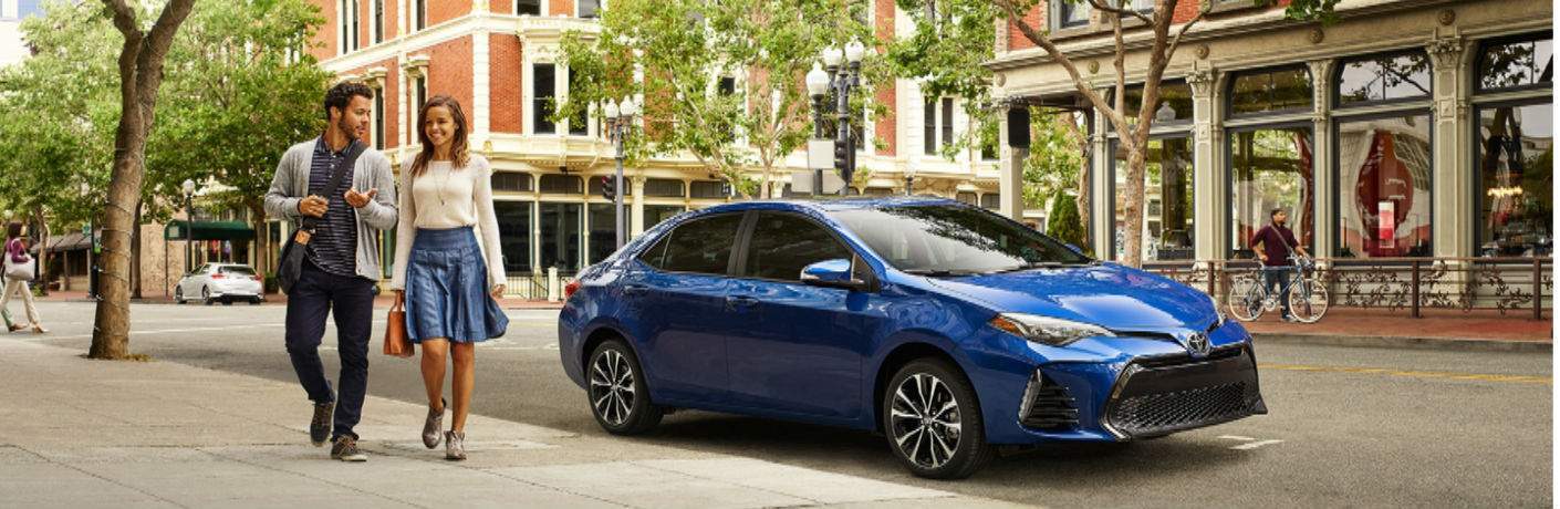 man and woman walking away from parked 2018 Toyota Corolla