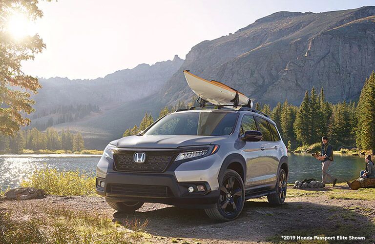 Silver 2019 Honda Passport Next to a River with a Kayak on the Roof and White *2019 Honda Passport Elite Shown Text