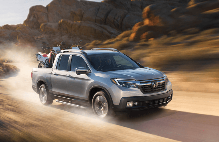 Silver 2020 Honda Ridgeline in a Desert with Dirt Bikes in Back