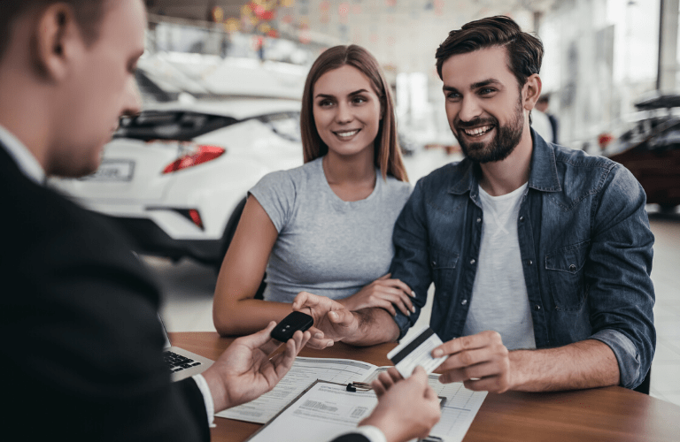 Couple signing papers at car dealership