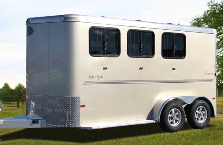 Front driver angle of a white Bumper Pull Sundowner horse trailer