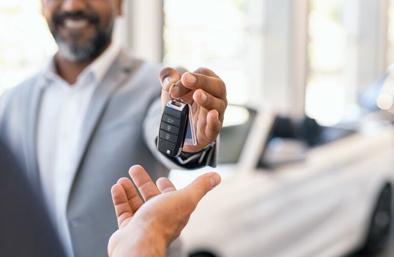 Happy car salesman handing over car keys