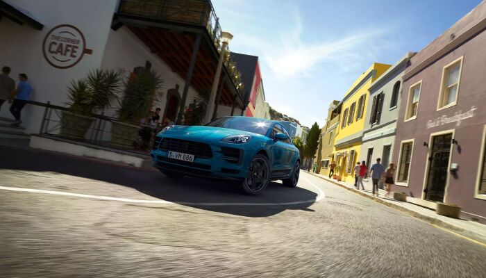 Blue Porsche Macan driving on city street