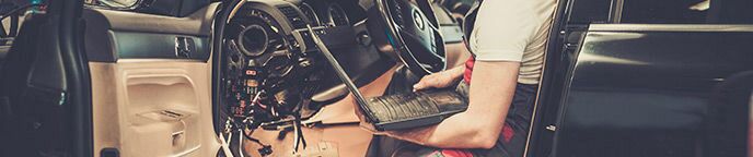 Technician Holding a Laptop Computer Inside a Car