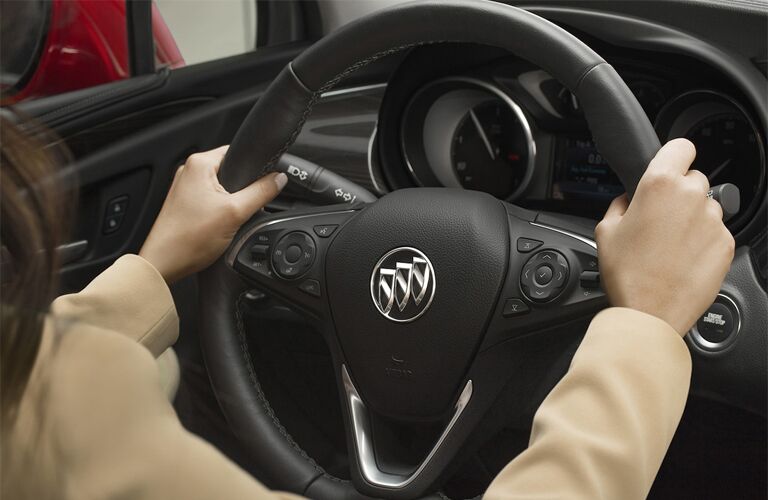 2019 Buick Envision interior closeup shot of driver's hands on the steering wheel with Buick badge