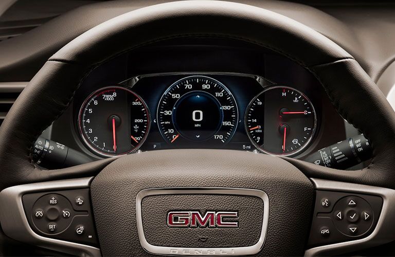 2019 GMC Acadia Denali exterior closeup shot of steering wheel branding and driver's display screen