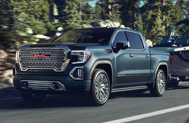2019 GMC Sierra 1500 Denali exterior shot towing a boat through a forest mountain trail