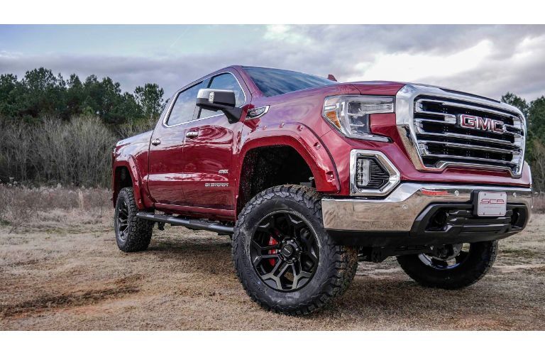 2019 GMC Apex SCA performance truck exterior shot with red paint color parked on a sparse and dry grass plain near tall brush