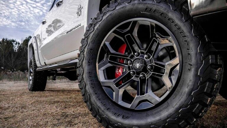 2019 SCA GMC Sierra Black Widow exterior closeup shot of unique tire and wheel design with Black Widow emblem badge