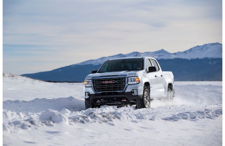 2021 GMC Canyon AT4 exterior shot with white paint color driving through a field of snow