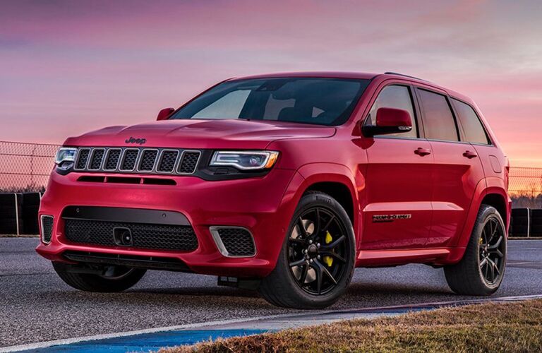 2019 Jeep Grand Cherokee exterior shot with red paint color parked on the edge of a race track