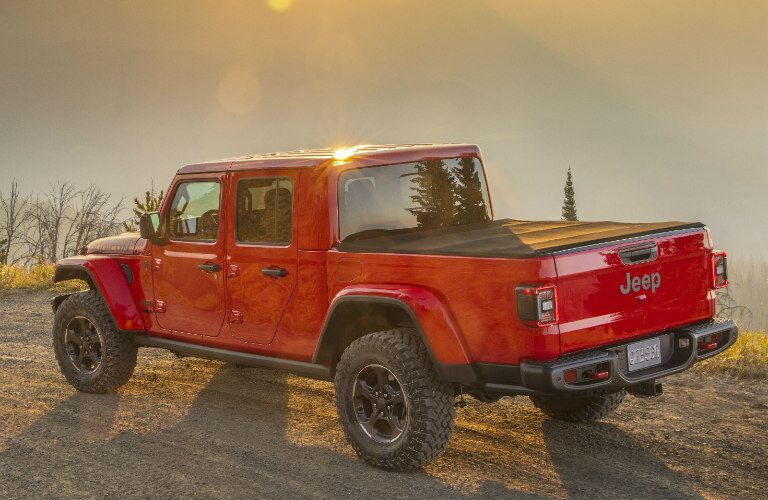 2020 Jeep Gladiator exterior rear shot with red paint color parked on a dirt cliff as the sun rises