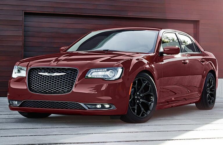 2019 Chrysler 300 exterior shot with dark red paint color parked on a wooden pier with a red wood cabin garage behind it