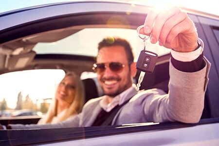 Image of a woman showing off the keys outside the window of her new vehicle