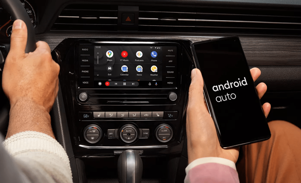 The hand of a person sitting in the front passenger seat of a VW holds their iPhone as it's connected to Android Auto
