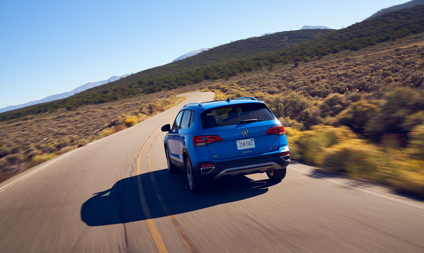 The back of a VW Taos driving along a two-lane highway.