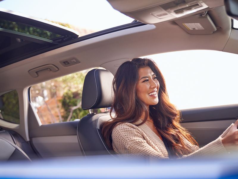 A smiling woman drives a VW Taos.
