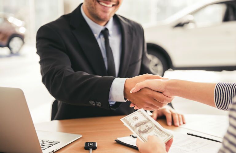 A photo of a person taking money from a dealership representative.